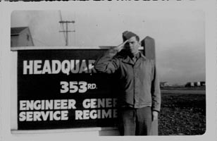 picture of Roman F. Klick standing in front of 353rd Headquarters sign and saluting